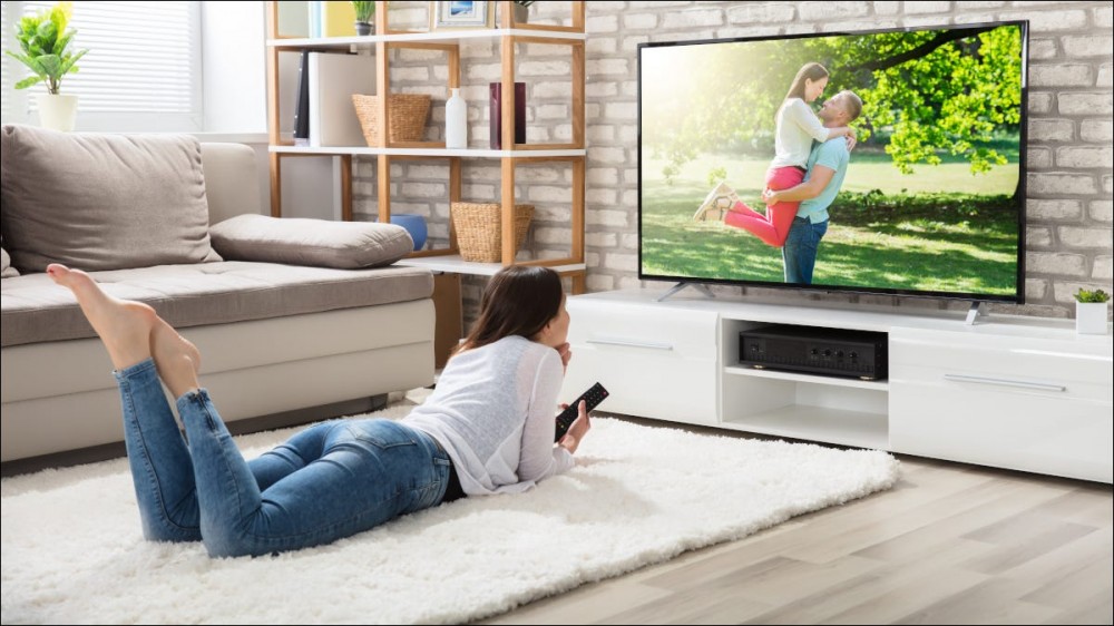 Young woman lying on floor watching TV